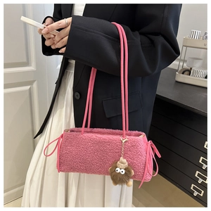 Detail of pink faux fur tote bag featuring a cute plush monster charm and long straps