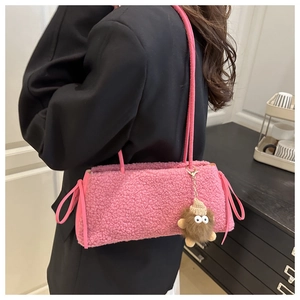 Detail of pink faux shearling tote bag with a cute monster pendant shown on shoulder