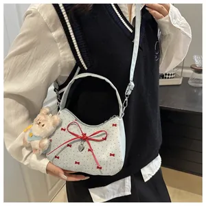 Détail du sac à bandoulière bleu clair avec nœuds rouges et breloque lapin