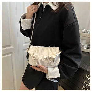 Détail du sac nuage plissé blanc avec bandoulière chaîne dorée et texture cuir lisse