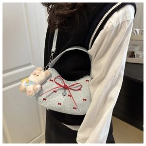 Détail d'un sac en toile bleu clair avec nœuds rouges et pendentif d'ours en peluche