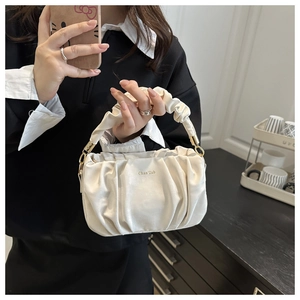 Détail du sac à main froncé avec des ferrures dorées et une texture blanc ivoire