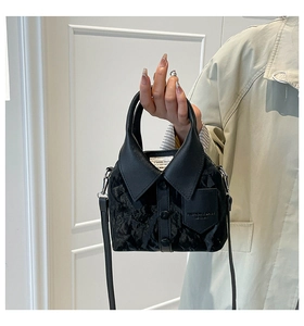 Detail of shirt-collar design on black leather handbag with buttons and embossed pocket