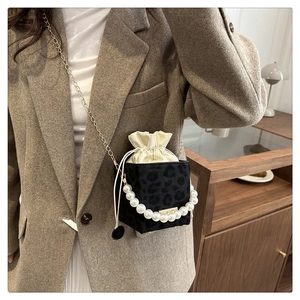 Detail of a cube crossbody bag with leopard print texture and pearl chain handle