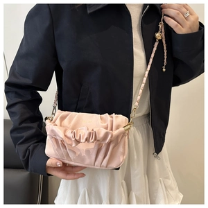 Détail du sac nuage plissé rose avec bandoulière chaîne dorée et cuir mat texturé