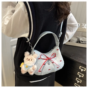 Détail du sac bleu clair à nœud avec pendentif ours en peluche et bandoulière réglable