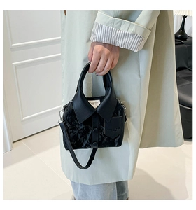 Detail of creative shirt-shaped black handbag with collar, buttons and pleated texture