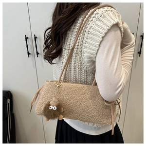 Detail of plush lamb-like shoulder bag in beige with monster charm and ribbon accent