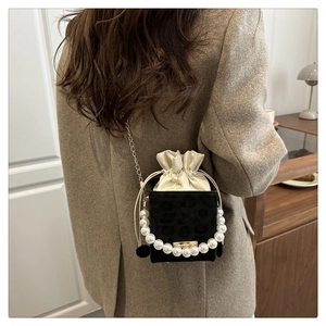Detail der Leoparden-Eimertasche mit Perlengriff und Goldkette auf einer Tweed-Jacke