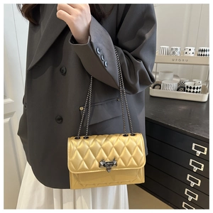 Detailed close-up of champagne gold quilted crossbody bag with unique bat-shaped metal lock
