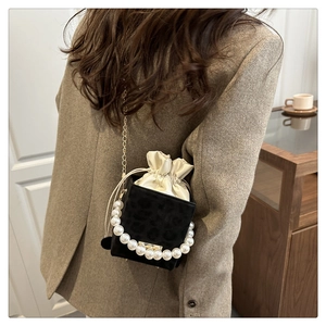 Leopard-Eimertasche mit Perlengriff und goldener Kette in eleganter Lifestyle-Umgebung