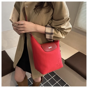 Detail of red canvas tote bag with embroidered puppy and bone shaped metal buckle
