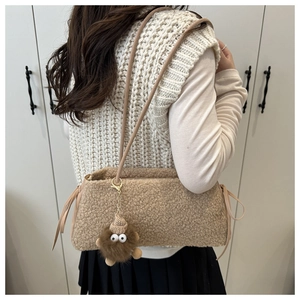 Détail d'un sac d'épaule en peluche avec un charm monstre mignon et cordon de serrage doux
