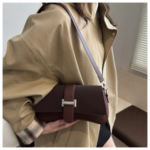 Nahaufnahme der dunkelbraunen Baguette-Tasche mit Silberschnalle getragen zum Khaki-Trenchcoat