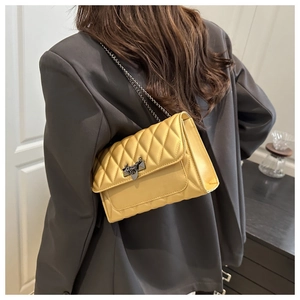 Détail du sac matelassé jaune avec texture losange et fermoir triangulaire unique