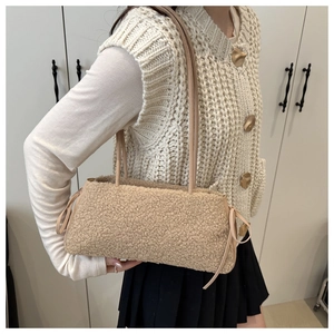 Detail of beige plush tote bag featuring side bow knots and slender leather shoulder straps