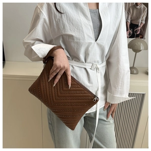 Close-up of brown leather envelope bag featuring a V-shaped studded design and metal zipper