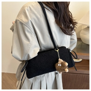 Detail view of black faux fur tote bag featuring a cute brown monster plush charm