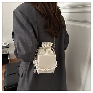 Détail du sac seau perle crème élégant avec fermeture à cordon et bandoulière chaîne
