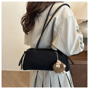 Detail of black plush tote bag featuring a cute brown monster charm and soft fuzzy texture