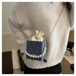 Detail of blue leopard print crossbody bag with pearl handle and gold chain strap