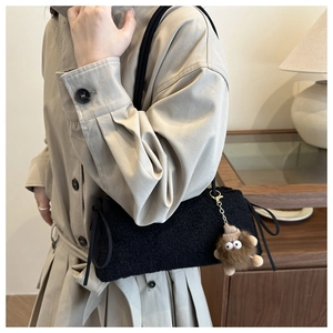 Detail of black faux shearling tote bag with side drawstring and cute monster charm