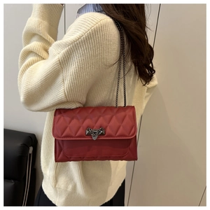 Detail of red quilted crossbody bag featuring classic diamond stitching and metal lock