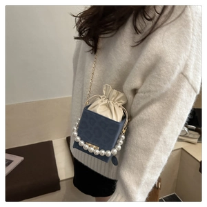 Detail of dark blue leopard print bucket bag with pearl handle and metal strap