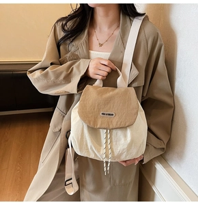Detail of nylon backpack with khaki flap and drawstring closure on trench coat model