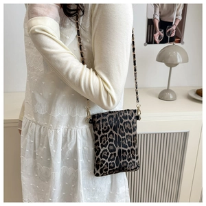 Detail of trendy leopard print mini crossbody bag with gold woven chain strap