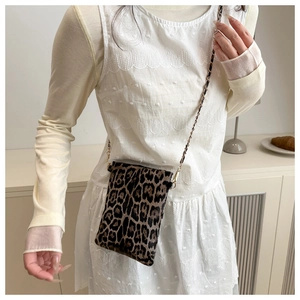 Detail of leopard print crossbody bag with gold chain strap on a model shoulder