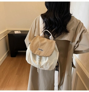 Detail of a beige and khaki backpack showing drawstring closure and printed logo