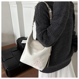 Detail of cream tote bag with puppy embroidery and silver bone-shaped metal buckle