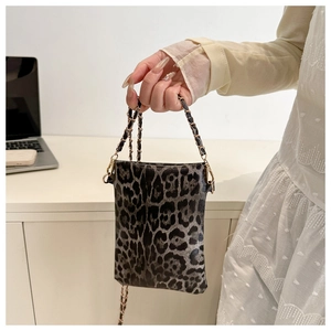 Detail of leopard print mini crossbody bag with golden chain strap held by hand