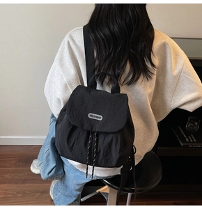 Detail shot of black nylon drawstring backpack with brand tag in a modern interior