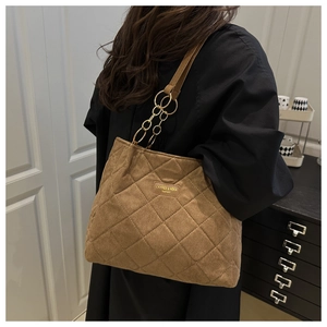 Detail of quilted brown tote bag showing gold ring connectors and fashion logo patch