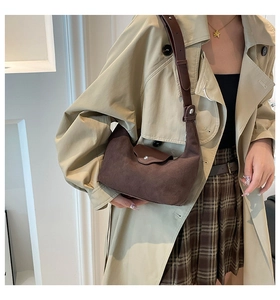 Detail of coffee suede hobo bag with leather flap and adjustable strap on a model
