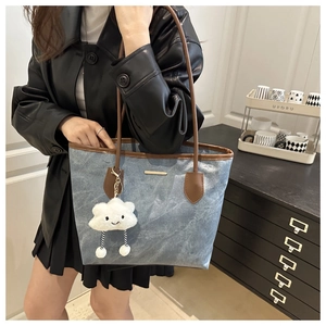 Blue denim tote bag detail showing leather trim and cute white cloud pendant