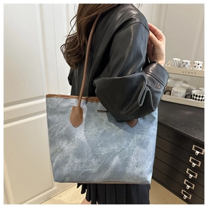 Detail of blue marble pattern tote bag featuring brown leather straps on model shoulder