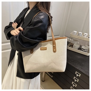 Detail of the large canvas tote bag showing cream fabric with brown leather trim and handles