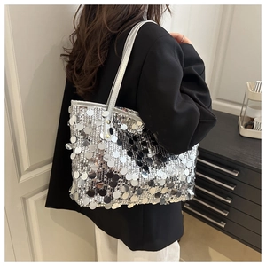 Dettaglio della borsa a tracolla con paillettes argento su un blazer nero elegante