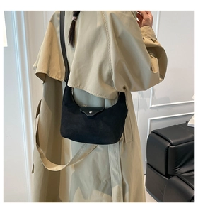 French style black suede crescent bag shown with a beige trench coat for a minimal look