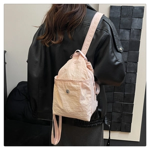 Detail of pink nylon waterproof crossbody bag showing textured fabric and magnetic snap