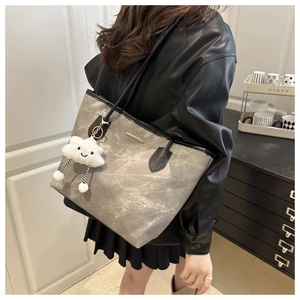 Detail of grey vintage textured tote bag with contrast black handles and cloud charm