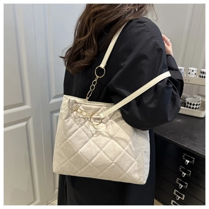 Detail der beige gesteppten Tote-Bag mit goldener Kette und feiner Rautensteppung-Struktur