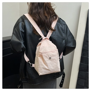 Pink nylon mini backpack with drawstring closure and metal logo buckle on a model