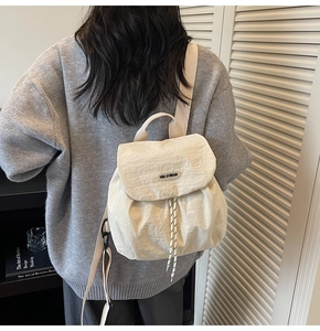 Detail of off-white drawstring backpack with textured fabric on model's back