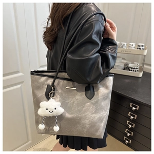 Close-up of stylish marble texture tote bag with plush cloud charm and long straps
