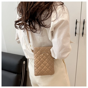Detailed close-up of quilted beige shoulder bag featuring a gold metal bow and chain strap