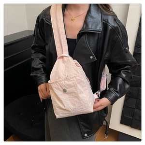 Detail of light pink wrinkled nylon chest bag with metallic logo and wide strap